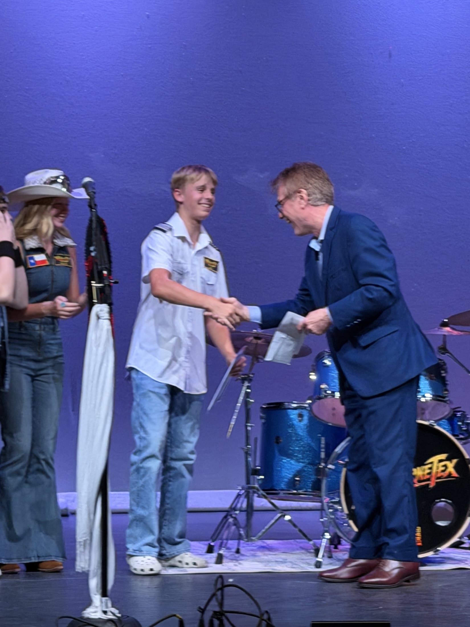 Lucas Rehl shakes hands with North Texas Performing Arts CEO Darrell Rodenbaugh after Airbourne Tex won the youth division of North Texas Got Talent on Sept. 13, 2026. Maryanne Hilton is at left. Photo: Airbourne Tex Team